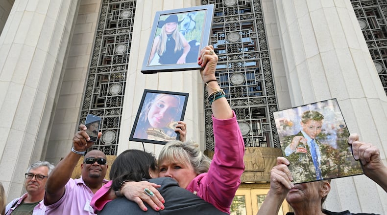 Lori Schott, center, is embraced as she holds up a photo of her daughter Annalee Schott, after the verdict in a landmark trial over whether social media platforms deliberately addict and harm children at Los Angeles Superior Court, Wednesday, March 25, 2026, in Los Angeles. (AP Photo/William Liang)