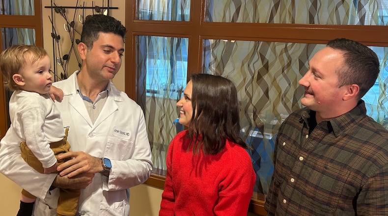 Dr. Amer Sayed holds Archer, 1, as he talks to Archer's parents Casey Gould and Ben Rosenberger during a reunion earlier this month at Atrium Medical Center. It was the first time the four of them had been together since Gould nearly died after child birth. RICK McCRABB/CONTRIBUTOR