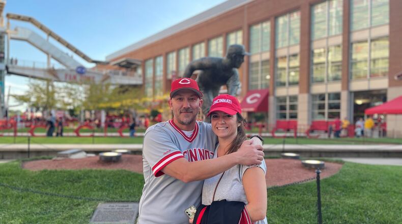 Ben Otto and his wife, Laura, celebrate his walk from their Fairfield home to Great American Ball Park Friday night. He walked 21.5 miles and raised nearly $12,000 for the Joe Nuxhall Miracle League. They posed in front of Nuxhall's statue. SUBMITTED PHOTO