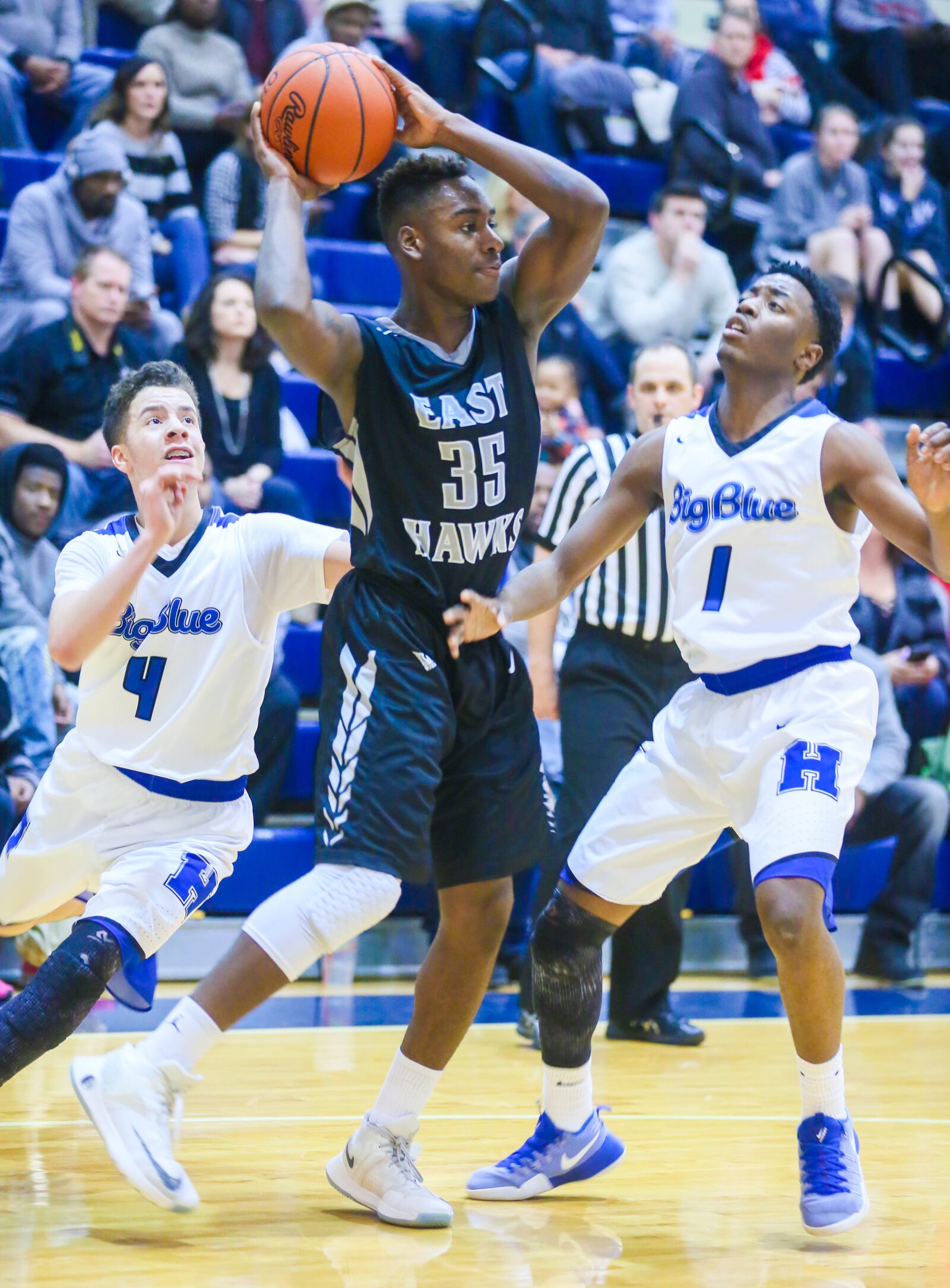 Lakota East guard Jarrett Cox (35) surveys the Hamilton defense while Big Blue’s Jaylen Robinson (4) and Daizure Morris (1) keep an eye on him Friday night at the Hamilton Athletic Center. GREG LYNCH/STAFF