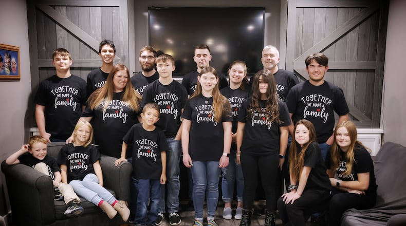 Christina and Richard Bennett are adopting two more kids on National Adoption Day bringing their total number of adoptions to seven. They stand and sit as a family in matching shirts. Back row, left to right: William, 14, Eli, 15, Austin, 23, Nathan, 20 and Richard. Middle row, left to right: Christina, Tyler, 14, Savannah, 13, McKenna, 20, Abigail, 12, and Isaiah, 15. Front row, left to right: Elijah, 6, Ashlynn, 8, Brayden, 8, Jocelynn, 10, and Samantha, 14. NICK GRAHAM/STAFF