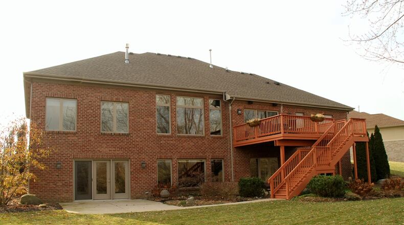 Triple patio doors open from the breakfast room to the balcony deck that has steps leading down to a concrete patio.