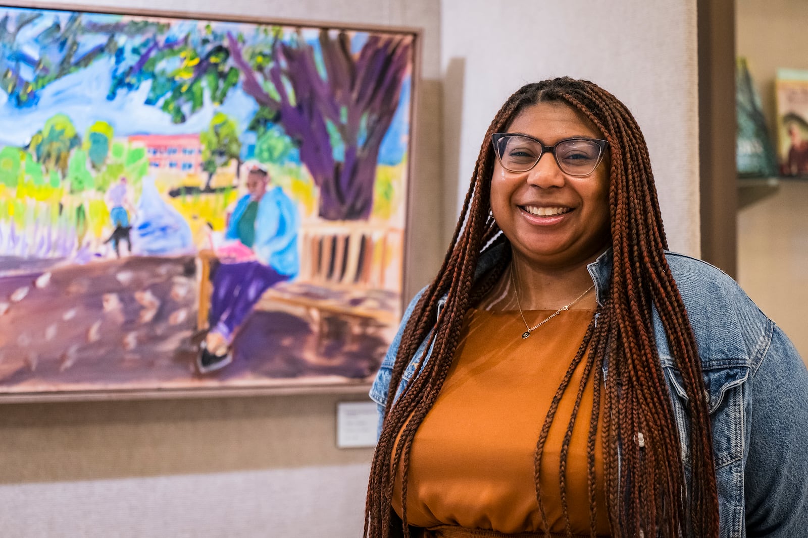 Devon Yarbrough, Digital Communications Manager at the George W. Bush Presidential Center, poses for a photo in front of a painting she is in by President George W. Bush on display in an exhibit at the George W. Bush Presidential Museum, Thursday, May 15, 2025, in Dallas. (AP Photo/Jessica Tobias)