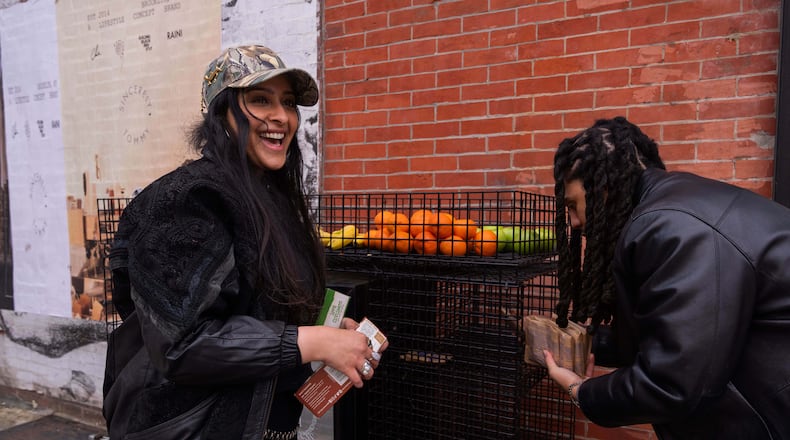 Kashish Ali and Elliott McKnight stock a One Love Community Fridge with food, Nov. 15, 2025, in Brooklyn, New York. (AP Photo/Adam Gray)