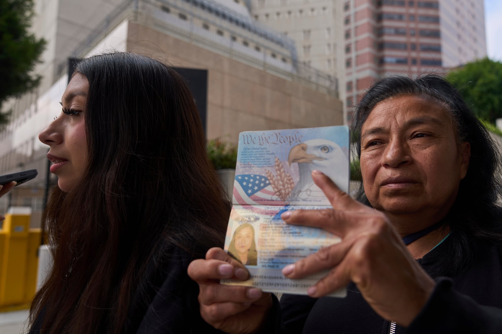 Margarita Velez, mother of Andrea Velez, 32, a U.S. citizen of South L.A, pictured on her current U.S. passport, is joined by her younger, daughter, Estrella Rosas, 17, left, looking for her location after ICE agents detained Andrea Velez during an immigration raid in downtown, outside the Metropolitan Detention Center in Los Angeles on Wednesday, June 25, 2025. (AP Photo/Damian Dovarganes)
