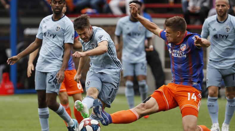 FC Cincinnati defender Nick Hagglund (14) deflects the ball off a shot on goal by Sporting Kansas City midfielder Kelyn Rowe (11) in the first half of an MLS soccer match, Sunday, April 7, 2019, in Cincinnati. (AP Photo/John Minchillo)