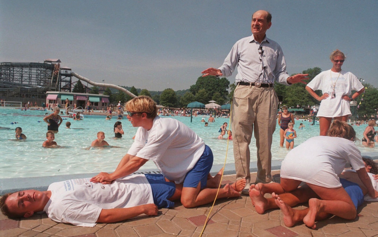 FILE - Dr. Henry J. Heimlich uses lifegaurds at Coney Island swimming pool in suburban Cincinnati on Friday, July 9, 1999, to demonstrate how the Heimlich maneuver can help save people from drowning. (AP Photo/Tony Tribble, File)