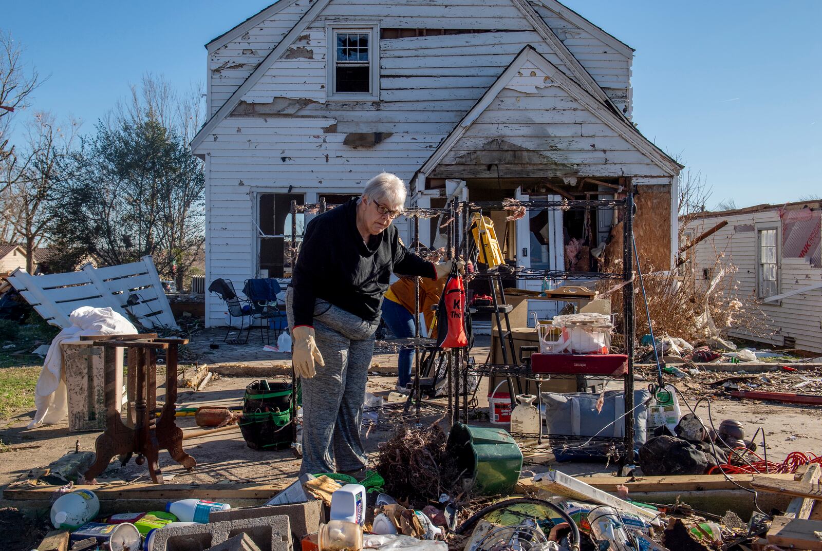 Martha Thomas sorts salvaged items outside of her home in Mayfield, Ky. on Monday, Dec. 13, 2021, after a tornado swept across the region. Volunteers were on site Monday to help with cleanup. (Johnny Milano/The New York Times)