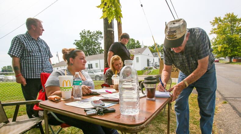 Steve Allen signs a list in support of community members who are taking a stand against drugs in their Hamilton neighborhood, started by Denny Matheny on Parkamo Avenue. GREG LYNCH / STAFF