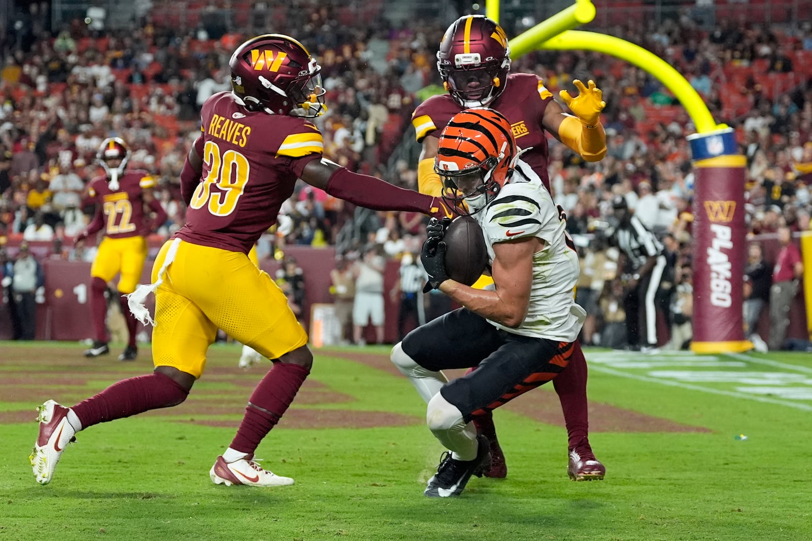Cincinnati Bengals wide receiver Charlie Jones (15) catches a touchdown pass as Washington Commanders safety Jeremy Reaves (39) and cornerback Noah Igbinoghene, top right, defend during the first half of a preseason NFL football game Monday, Aug. 18, 2025, in Landover, Md. (AP Photo/Stephanie Scarbrough)