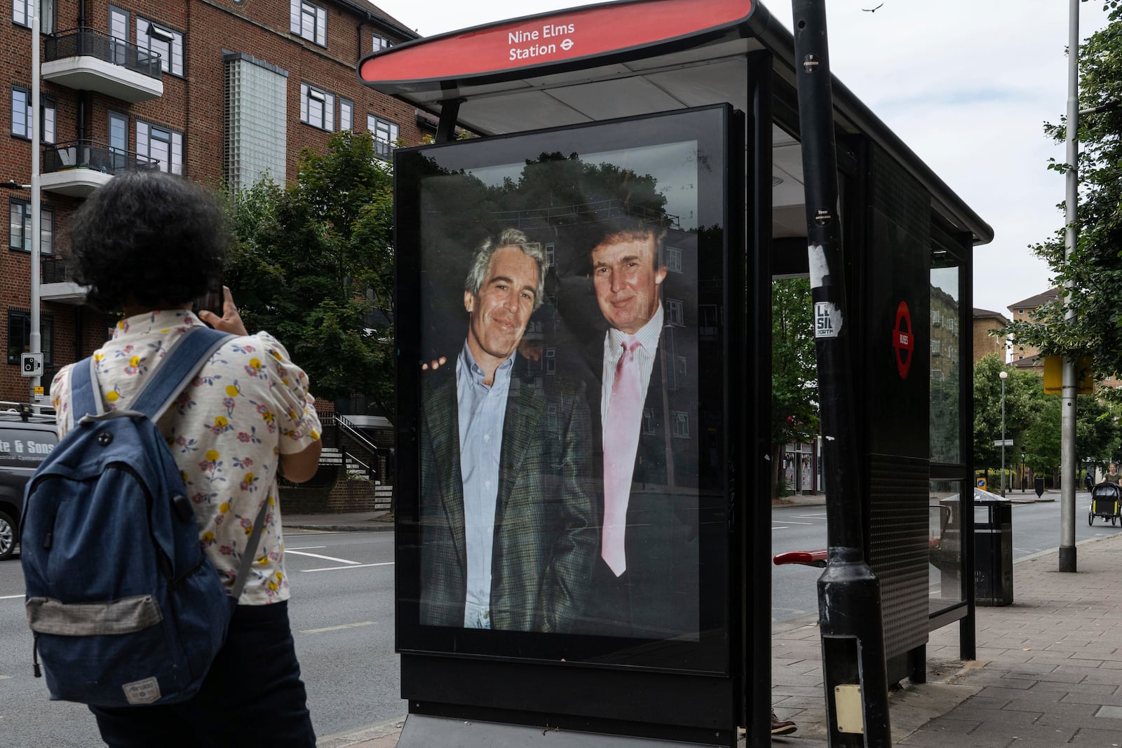 Commuters walk past a bus stop near Nine Elms Station as activists put up a poster showing President Donald Trump and Jeffrey Epstein near the US Embassy in London, Thursday, July 17, 2025.(AP Photo/Thomas Krych)