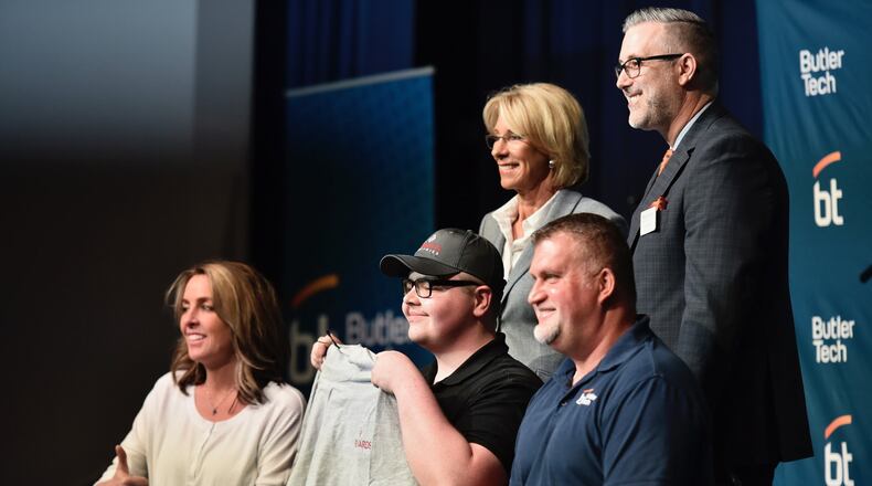 Butler Tech student Randy Owens, middle, holds up a shirt for his new employer, Richards Industries, during a signing day ceremony at Butler Tech in Fairfield Township Friday, April 12, 2019. Twenty-five students signed to work for companies they did internships with during the school year. NICK GRAHAM/STAFF