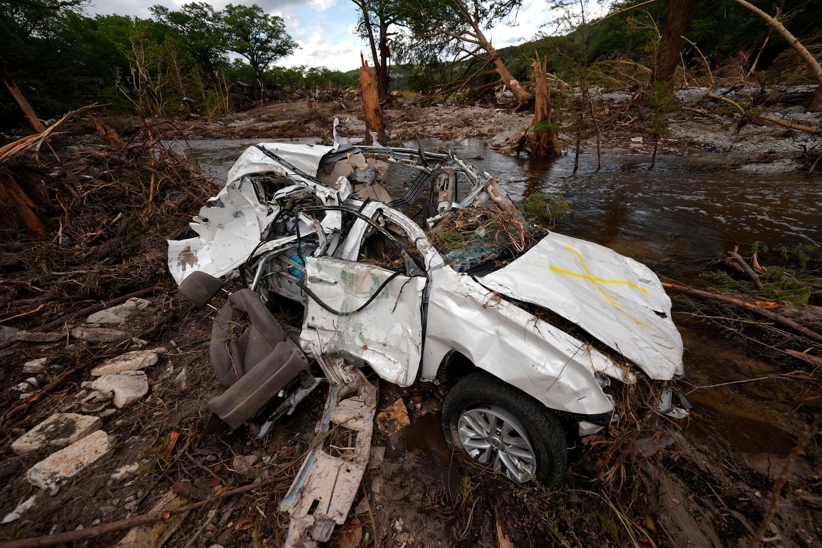 A destroyed vehicle sits next to the Guadalupe River on Wednesday, July 9, 2025, in Hunt, Texas, after a flash flood swept through the area. (AP Photo/Gerald Herbert)