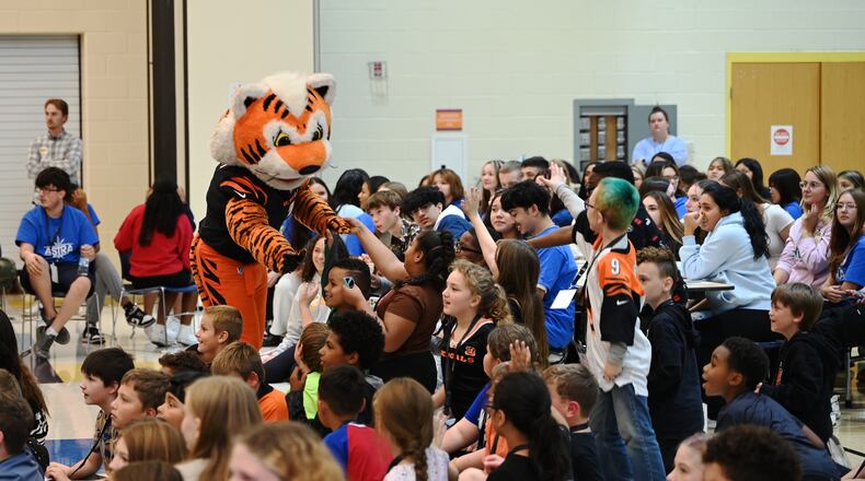 Just a Pair of Shoes, a nonprofit organization that distributes free high-end shoes distributed 120 pairs to students at Highland Elementary School in the Hamilton City School District. The event was sponsored by Kettering Health and the Cincinnati Bengals. After receiving the shoes, the students put them on and tried them out. Pictured is Bengals mascot Who Dey greeting Highland Elementary students before they received a free pair of shoes and three pairs of Bombas socks.  MICHAEL D. PITMAN/STAFF