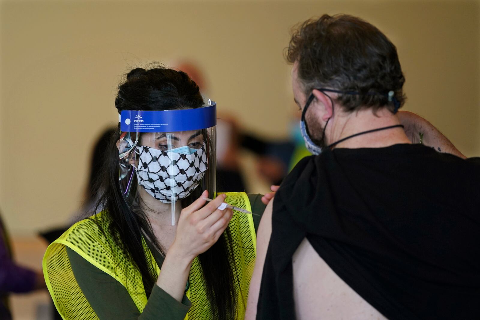 Pete Graham, right, receives the first dose of the Moderna COVID-19 vaccine from a volunteer worker, Friday, Feb. 26, 2021, at a mass vaccination clinic at Seattle University in Seattle. Graham was able to get the vaccine because he had worked a shift at the clinic as a volunteer earlier in the day. As states ramp up vaccination distribution in the fight against the coronavirus, volunteers are needed to do everything from direct traffic to check people in to keep vaccination sites running smoothly. In return for their work, they're often given a shot — including those who are young and healthy and may not have otherwise been able to receive the shot until later in the year. (AP Photo/Ted S. Warren)