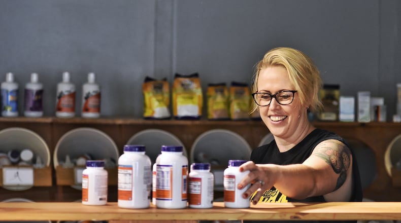 Owner Jamie Benge places product on shelves ahead of the ribbon cutting for Soulshine Wellness on Main Thursday, Sept. 3, 2020 at 508 Main Street in Hamilton. NICK GRAHAM / STAFF