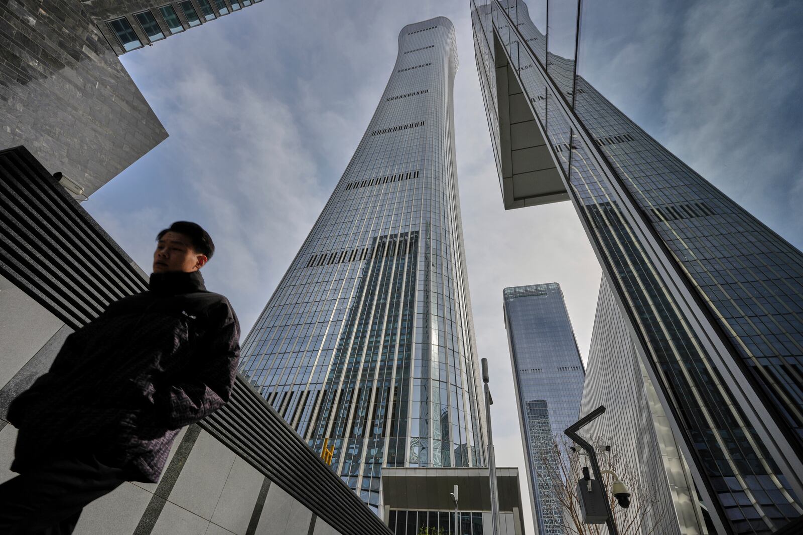 A man walks by high rise office buildings in the central business district, in Beijing, Tuesday, April 8, 2025. (AP Photo/Andy Wong)