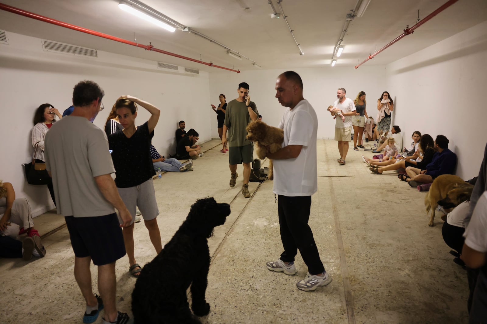People take shelter as a siren sounds a warning following a missiles that were launched from Iran, in Tel Aviv, Israel, on Friday, June 13, 202 5. (AP Photo/Tomer Appelbaum)