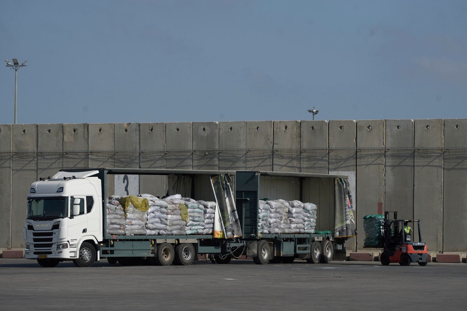 A worker unloads cargo from a truck carrying humanitarian aid for the Gaza Strip at the offload area of the Kerem Shalom border crossing between Israel and Gaza, southern Israel, Thursday, May 22, 2025. (AP Photo/Leo Correa)