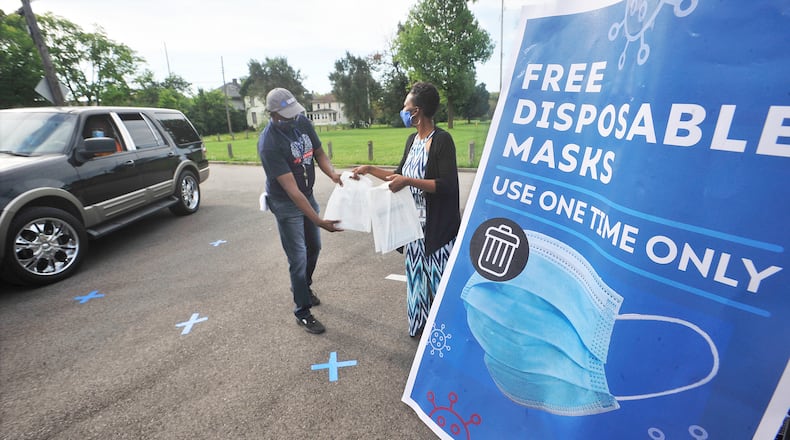 Gilbert Ghand, left, and Angela Boykin, with Dayton & Montgomery Public Health, help to giveaway free disposable mask Monday, Aug. 17, 2020, at the Mount Olive Baptist Church. MARSHALL GORBY\STAFF