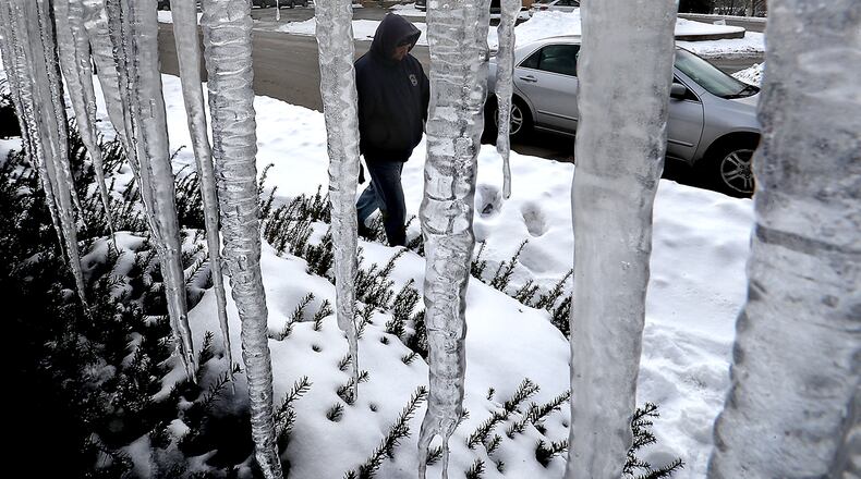 A man walks along Chestnut Avenue past a row of giant icicles, some nearly touching the ground, hanging off the side of the Hickory Inn restaurant Friday morning. BILL LACKEY/STAFF