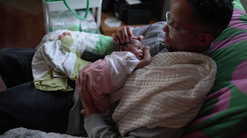 First-time dad JaKobi Burton holds his newborn daughter, Phoenix RyZen Reign Burton, at their home in Indianapolis, Nov. 13, 2025. (AP Photo/Obed Lamy)