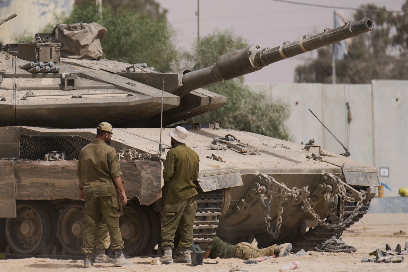 Israeli soldiers work on a tank at a staging area near the border with the Gaza Strip, in southern Israel, Tuesday, July 1, 2025. (AP Photo/Ariel Schalit)