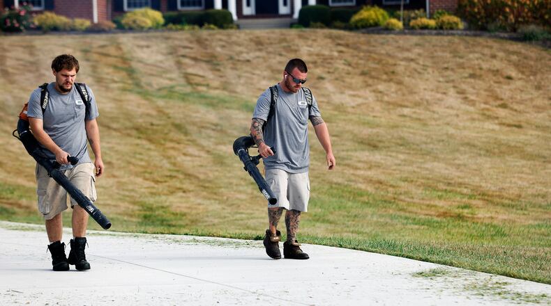 Dunham's Lawn Care employees Hayden Pond and Joshua Jackson blow grass off the driveway of a Greene County customer Wednesday, Sept. 25, 2024. The drought that has swept through Ohio and worsened over the past several weeks has turned area lawns brown and brittle. MARSHALL GORBY/STAFF