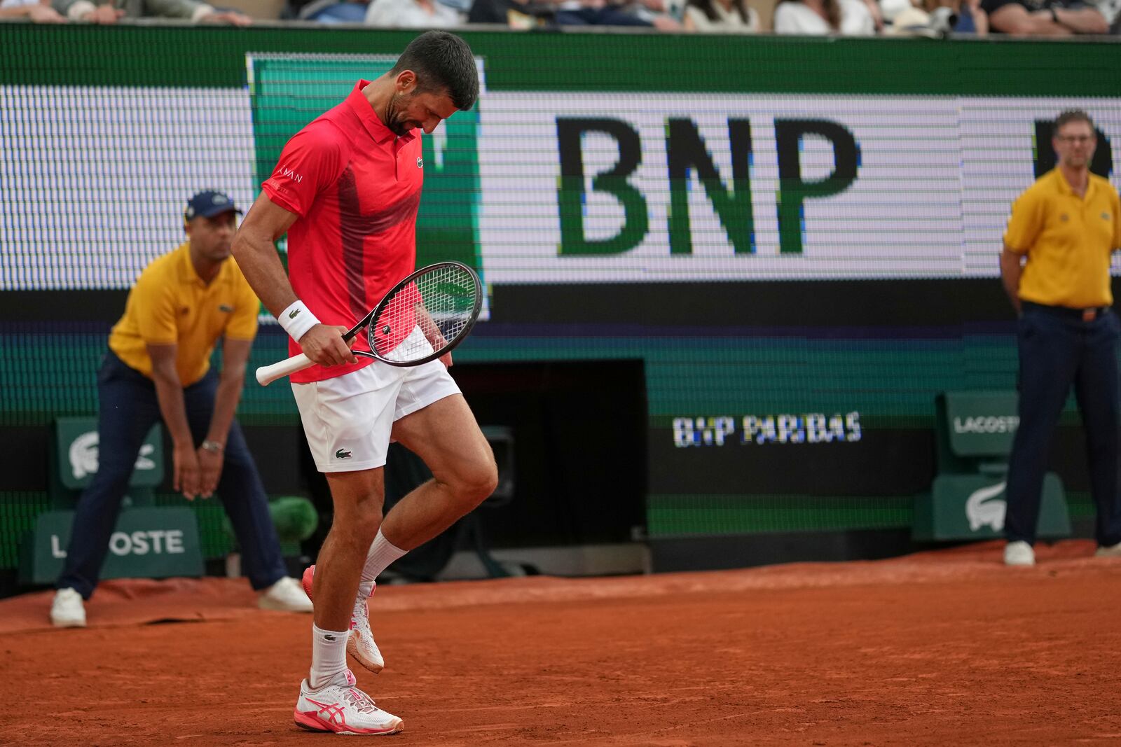 Serbia's Novak Djokovic limps on the court before receiving medical assistance during his second round match of the French Tennis Open against France's Corentin Moutet, at the Roland-Garros stadium, in Paris, Thursday, May 29, 2025. (AP Photo/Christophe Ena)