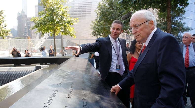 FILE - Former U.S. Vice President Dick Cheney, right, listens to 9/11 Memorial President Joe Daniels, center, as he looks at one of the panels inscribed with the names of the attack victims during a visit to the 9/11 memorial plaza in the World Trade Center site in New York Monday, Sept. 12, 2011, on the first day that the memorial was opened to the public. (AP Photo/Mike Segar, file)