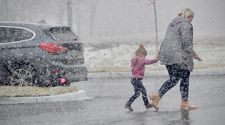 The first snowfall of the season as people scrambling Monday, Dec. 18, 2023 like these two on E. Main St. in New Lebanon at the Dollar General. MARSHALL GORBY \STAFF