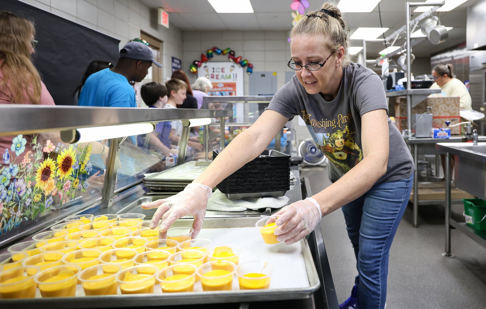 Amber Bowling, a food and nutrition worker, grabs cups of cheese sauce to put out for children to eat on Friday, Aug. 1 during a summer lunch program at Greenmont Elementary School in Kettering. Kettering City Schools organized the summer lunch program, which ran from June 2 to Friday. BRYANT BILLING / STAFF