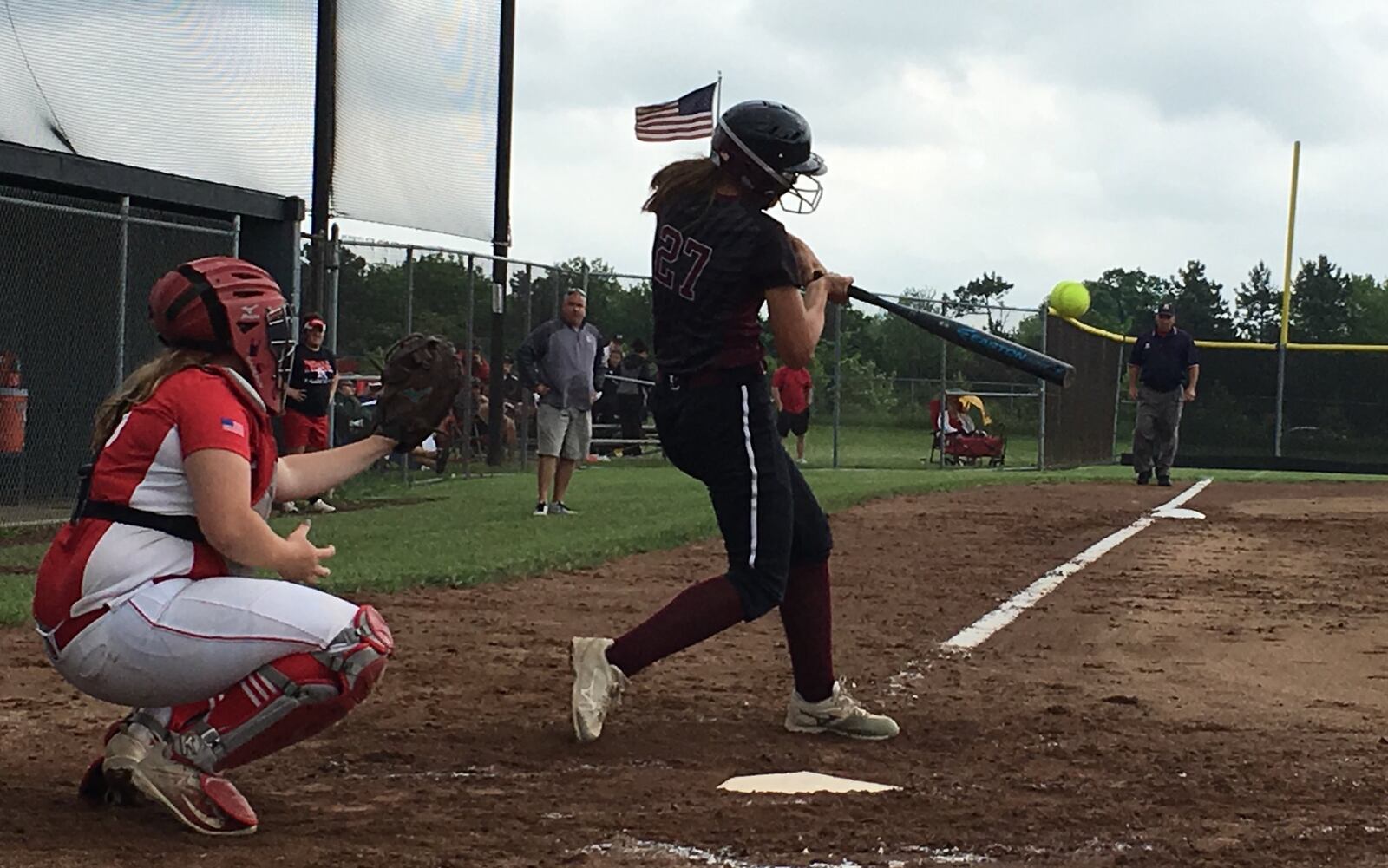 Lebanon’s Madison Hartman (27) connects with the ball as Warriors coach Brian Kindell watches from the third-base coaching box during Saturday’s Division I district final against Fairfield at Lakota East. The Indians’ catcher is Natalie Elliott. RICK CASSANO/STAFF