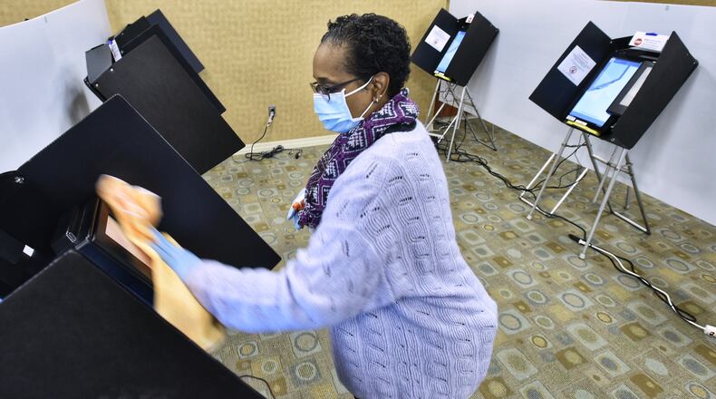 Butler County Board of Elections volunteer Jillynn Whitlow cleans voting machines on the first day of early voting Tuesday, October 6, 2020 in Hamilton. NICK GRAHAM / STAFF