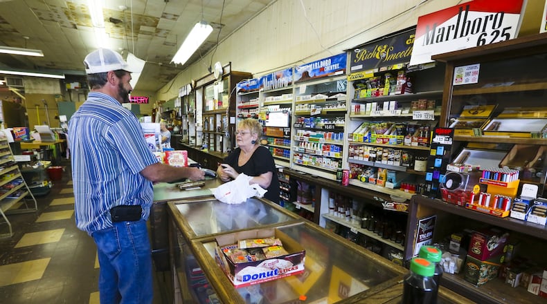 Teresa Jenkins works behind the counter of Tom’s Cigar Store in Hamilton. GREG LYNCH / STAFF