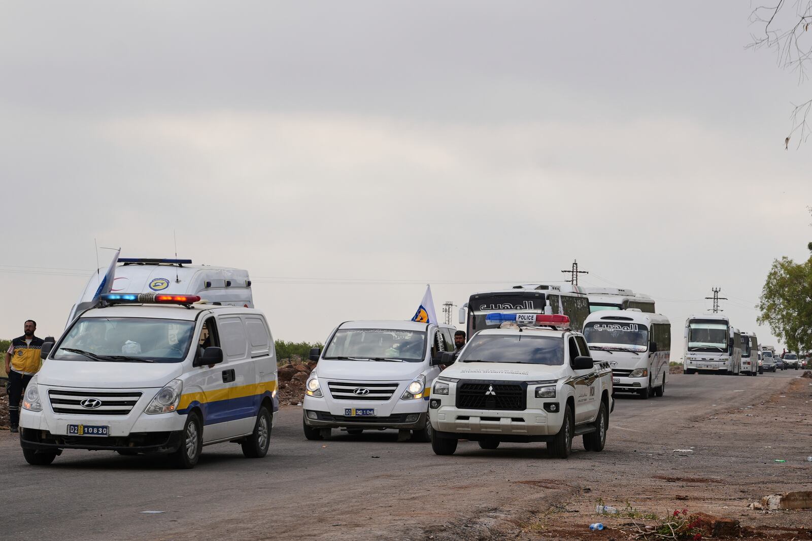 Syrian Bedouin families ride in a convoy led by Red Crescent vehicles in Busra al-Harir, heading to Daraa after being evacuated from Sweida following more than a week of violent clashes, Monday, July 21, 2025. (AP Photo/Malek Khattab)