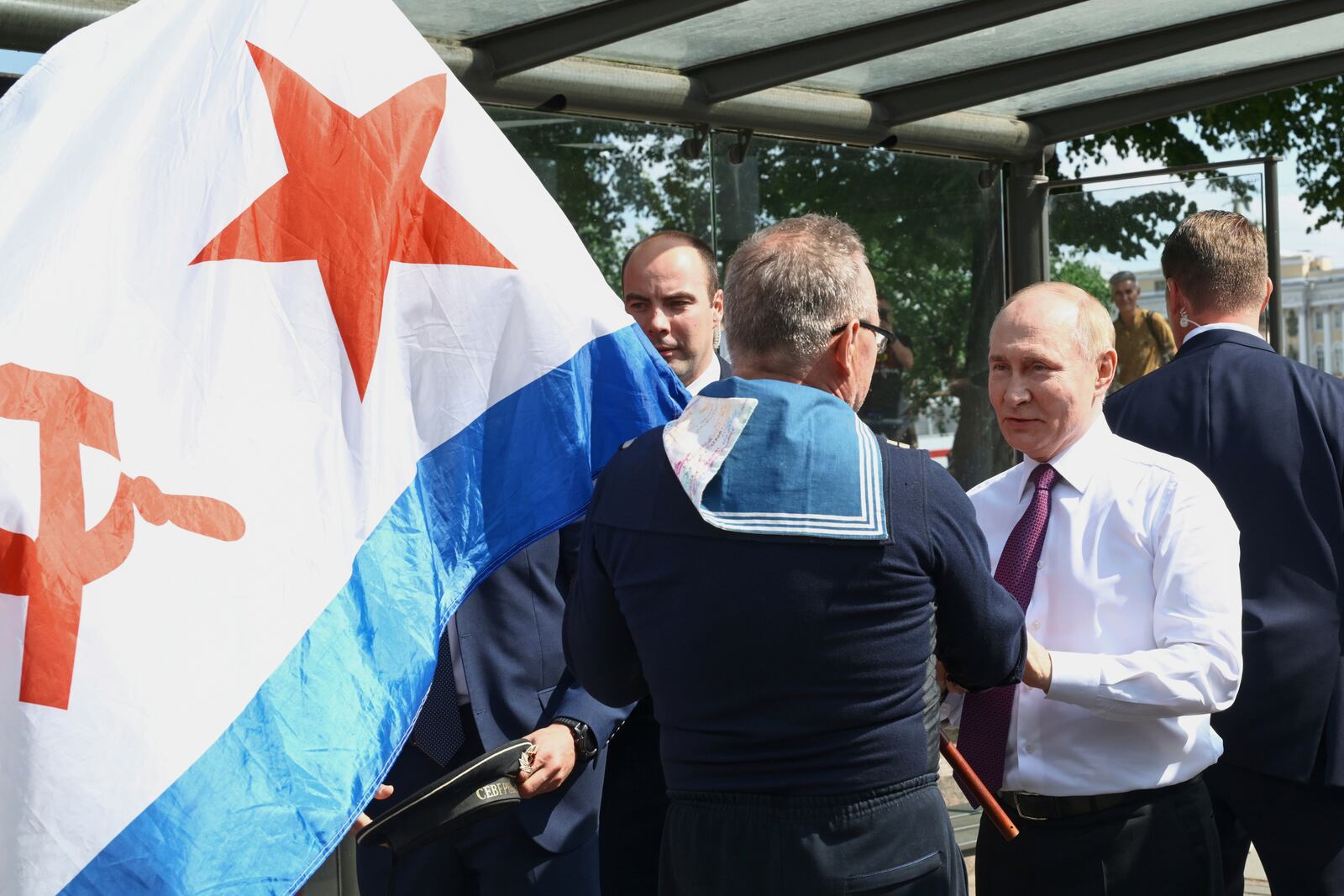 Russian President Vladimir Putin, right, congratulates a naval veteran holding a Soviet Nay flag, on Navy Day in St. Petersburg, Russia, on Sunday, July 27, 2025. (Alexei Danichev, Sputnik, Kremlin Pool Photo via AP)
