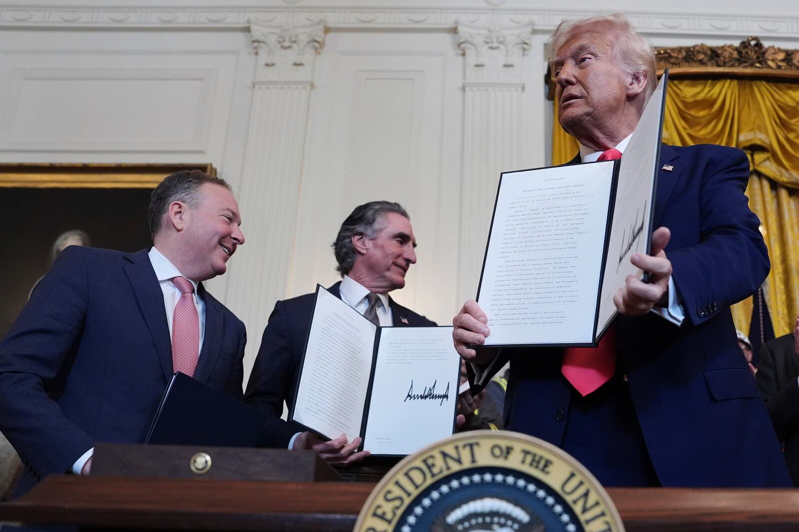 President Donald Trump holds a signed an executive order during an event in the East Room of the White House, Tuesday, April 8, 2025, in Washington, as Environmental Protection Agency director Lee Zeldin and Interior Secretary Doug Burgum watch. (AP Photo/Evan Vucci)