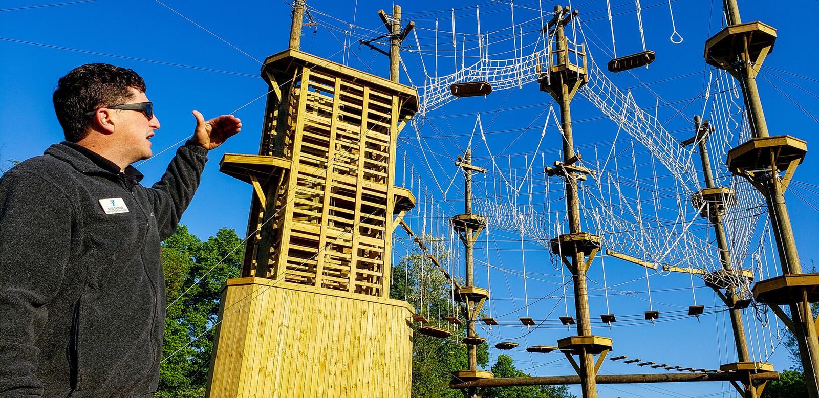 Pete Fasano, executive director of Camp Campbell Gard, shows off the at the Great Miami Valley YMCA's high ropes course now open at Camp Campbell Gard Wednesday, May 15, 2019 on Augspurger Road in St. Clair Township. The course stands nearly fifty feet tall with three levels of elements ranging in difficulty. There is also a climbing wall, zip line, giant swing and more. The course has a universal access system allowing participants with all abilities, including those in wheel chairs, the opportunity to experience it. NICK GRAHAM/STAFF