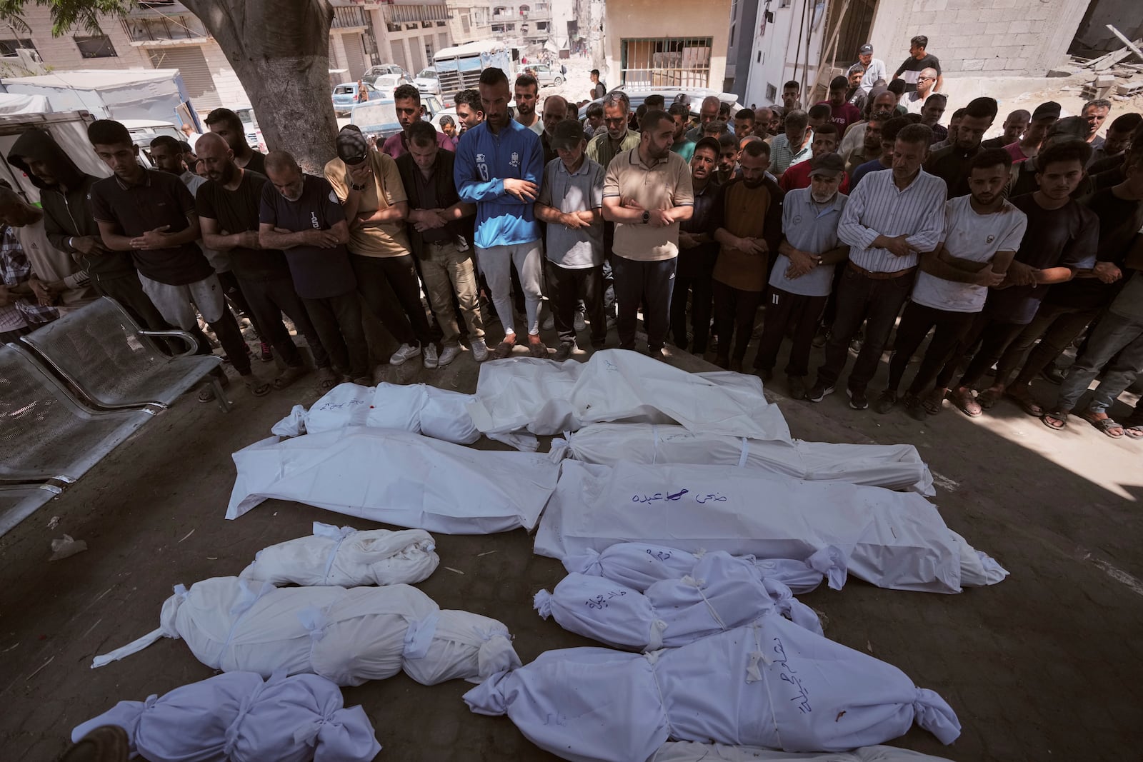 Mourners pray beside the bodies of Palestinians that were killed by an Israeli airstrike that struck a school used as a shelter, in Shifa Hospital in Gaza City, on Thursday, July 3, 2025. (AP Photo/Jehad Alshrafi)