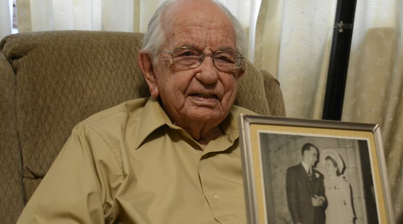 Paul E. Sallada will celebrate his 100th birthday on April 18, 2019. He sits in his Fairfield home with a wedding picture of him and his wife in 1942. MICHAEL D. PITMAN/STAFF