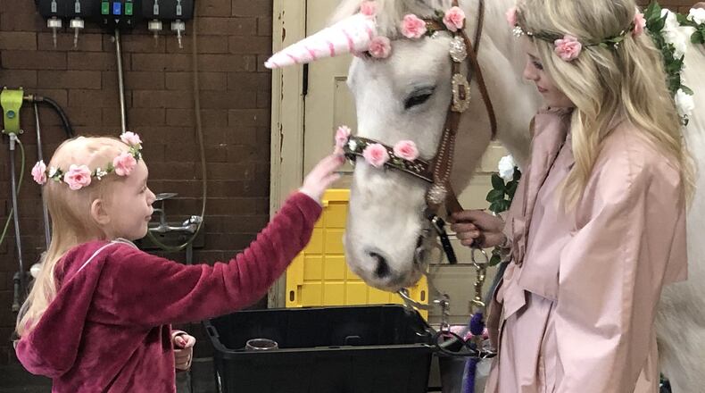 Naomi Short, then 8, of Hamilton, pets a horse that was decorated as a unicorn inside a Hamilton fire station. Naomi has been diagnosed with Stage 4 brain cancer and has a 30 percent chance of surviving. Lexi Durbin, 18, of Oxford, a freshman at Miami University Hamilton, dressed up as a princess. RICK McCRABB/STAFF