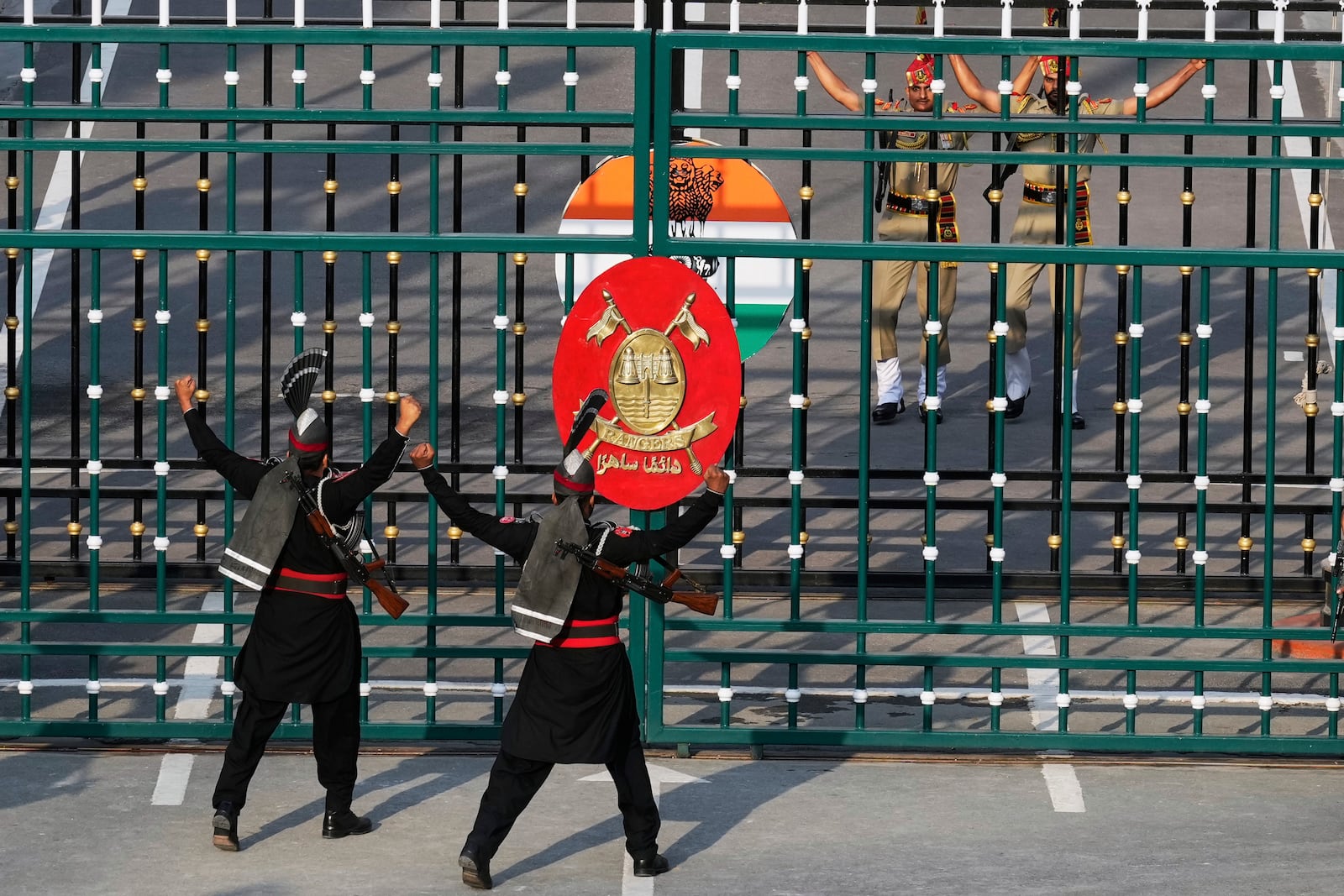 Pakistan's Rangers soldiers, in black, and Indian Border Security Forces soldiers, behind gate, gesture each others during a daily closing ceremony at the Wagah, a joint post on the Pakistan and India border, near Lahore, Pakistan, Monday, May 5, 2025. (AP Photo/K.M. Chaudary)