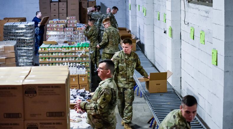 Members of the Ohio Army National Guard pack boxes of food on March 23 at Shared Harvest Food Bank in Fairfield. The Ohio Army National Guard was activated and helped food banks distribute to those in need, but federal funding is expected to run out. Ohio Gov. Mike DeWine has committed to having the National Guard continue assisting food banks. NICK GRAHAM/FILE