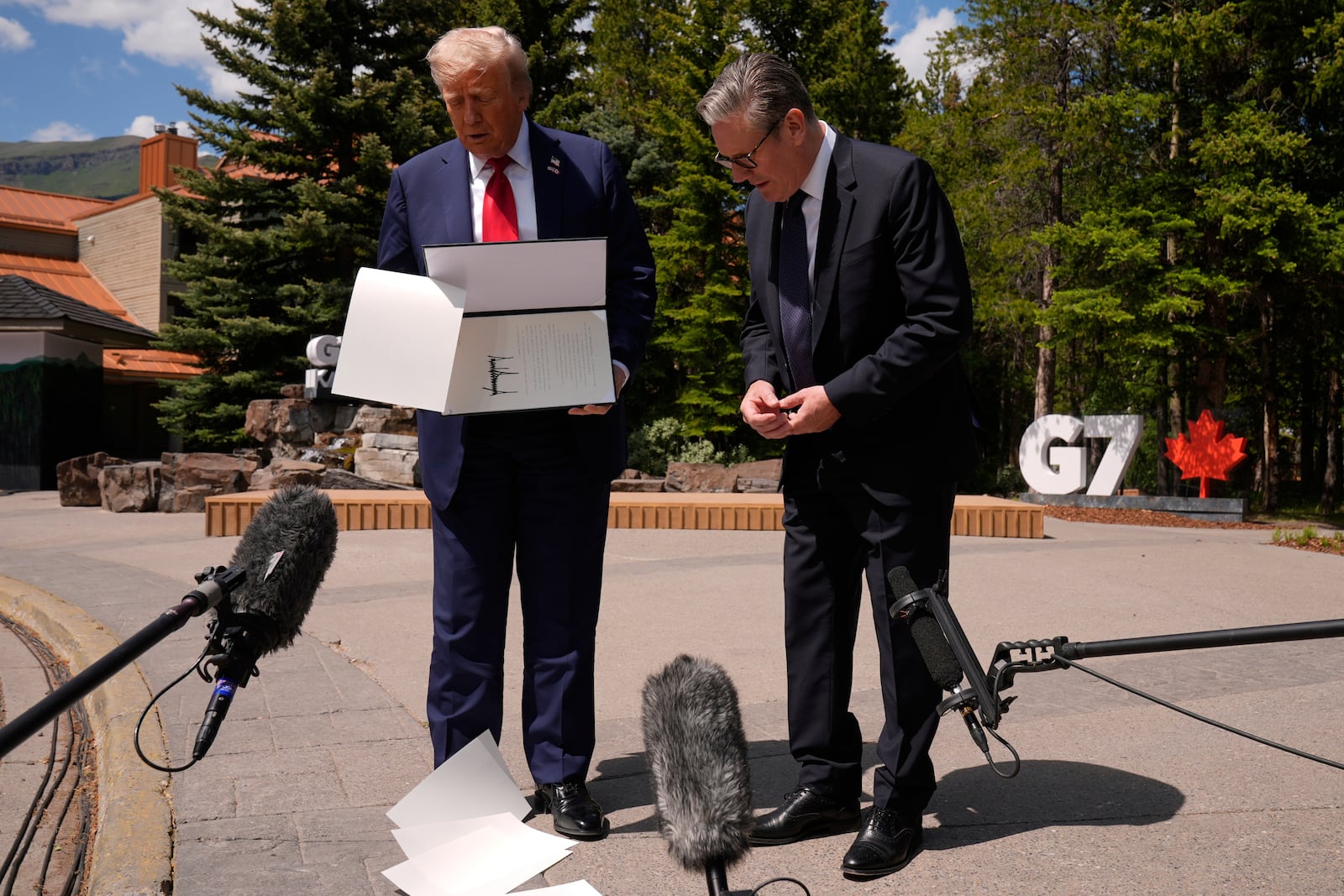 President Donald Trump drops papers as he meets with Britain's Prime Minister Keir Starmer on the sidelines of the G7 Summit, Monday, June 16, 2025, in Kananaskis, Canada. (AP Photo/Mark Schiefelbein)