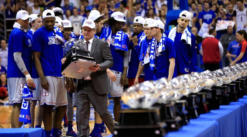 FILE - In this Feb. 22, 2017, file photo, Kansas coach Bill Self carries his 13th Big 12 championship trophy following the team's NCAA college basketball game against TCU in Lawrence, Kan. In the most damaging instance of legal trouble at Kansas this season, police investigated a reported rape at the dorm that houses the basketball team. No charges have been filed. From there, more headlines kept piling up involving no fewer than four players. Self said he's proud his team has rallied despite the steady stream of issues. (AP Photo/Orlin Wagner, File)