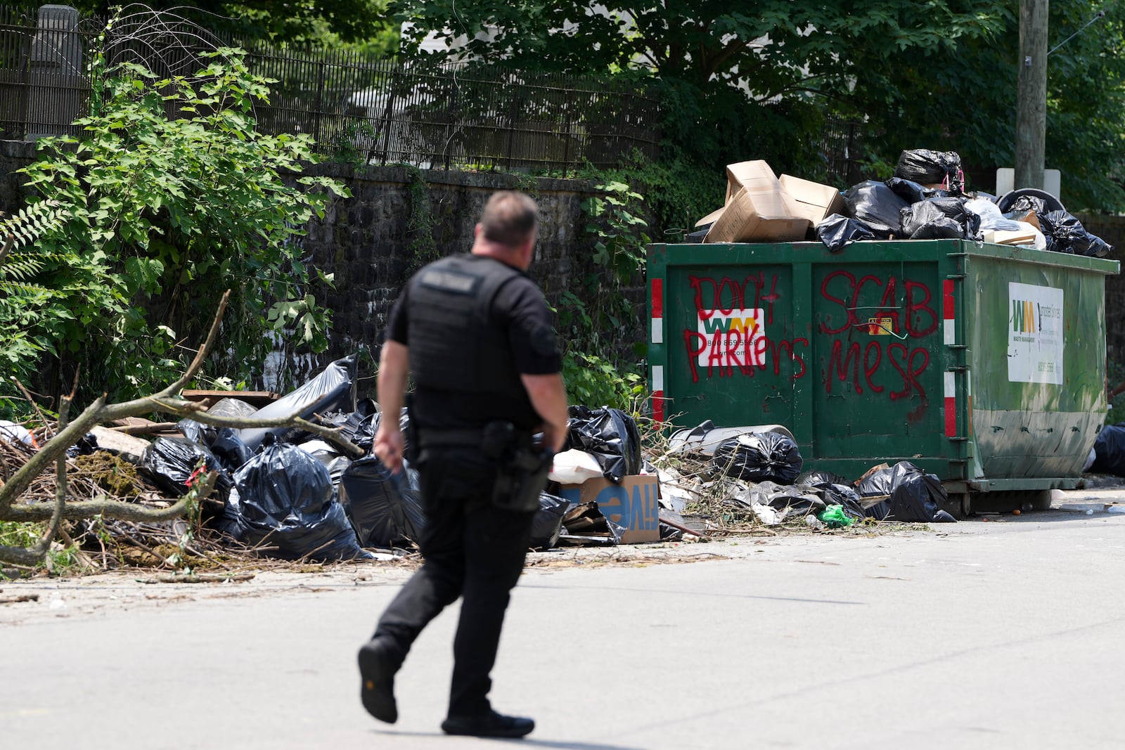 A police officer walks past a garbage collection site, Wednesday, July 9, 2025, in Philadelphia. (AP Photo/Matt Slocum)