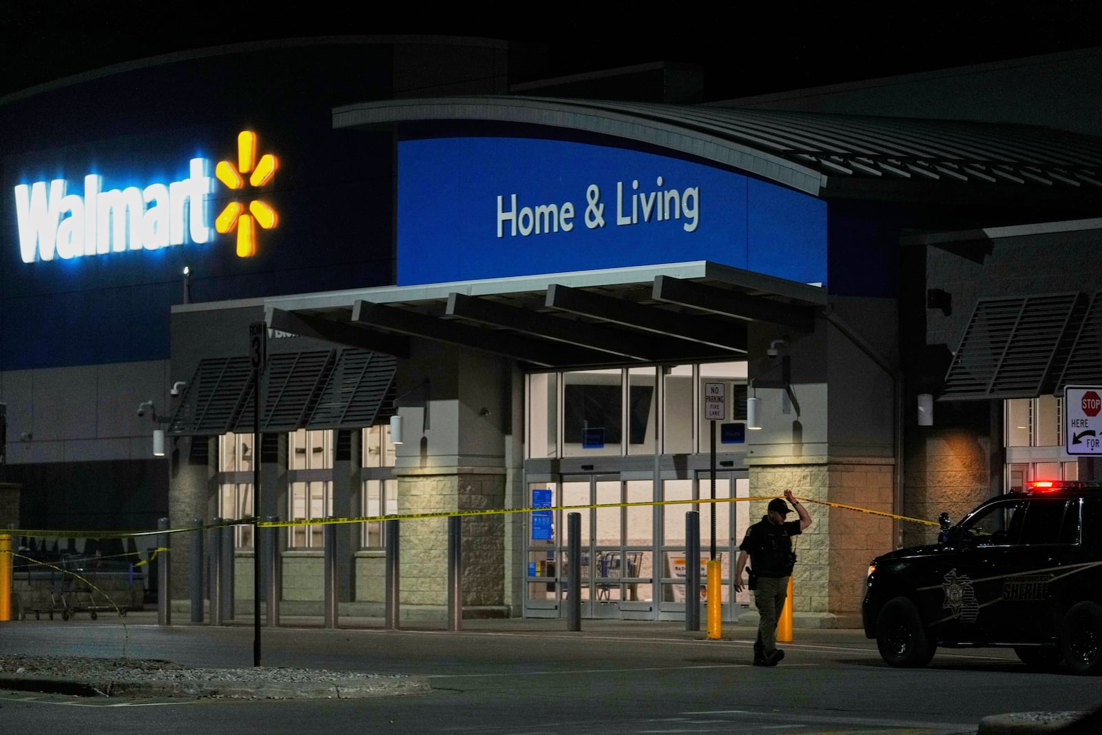 Law enforcement officers cross caution tape outside a Walmart where 11 people were stabbed in a violent attack Saturday, July 26, 2025, in Traverse City, Mich (AP Photo/Ryan Sun)