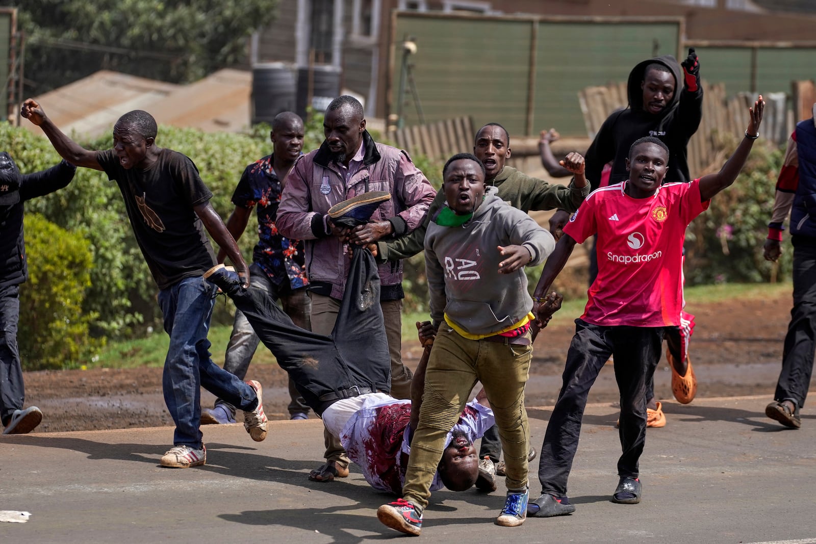 Protester carry a man who the crowd claimed had been shot by police, during the historic 1990 Saba Saba, a Swahili word that means seven seven, protests for democratic reforms in the Kangemi slum of Nairobi, Kenya Monday, July 7, 2025. (AP Photo/Brian Inganga)