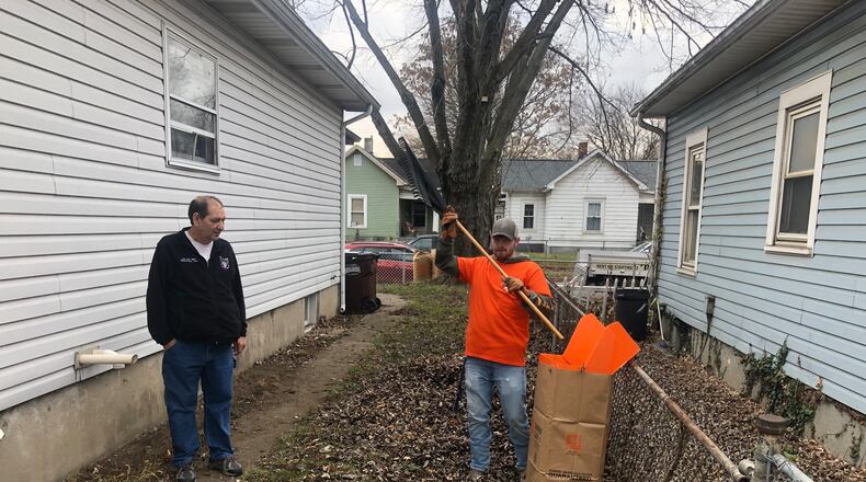 Todd Singh, 54, a U.S. Navy veteran with disabilities, watches Monday morning as Home Depot volunteer Noah Hampton, of Somerville, bags leaves. RICK McCRABB/STAFF
